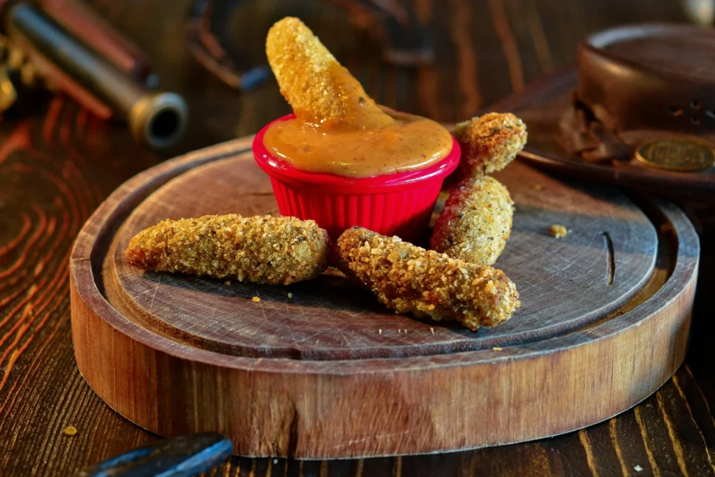 Krokante airfryer snacks met kaassticks en dipsaus op houten plank