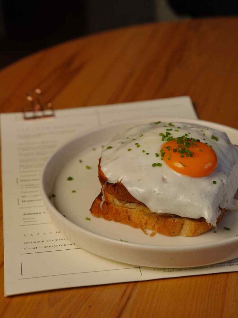 Toast met gebakken ei en bieslook op een wit bord.